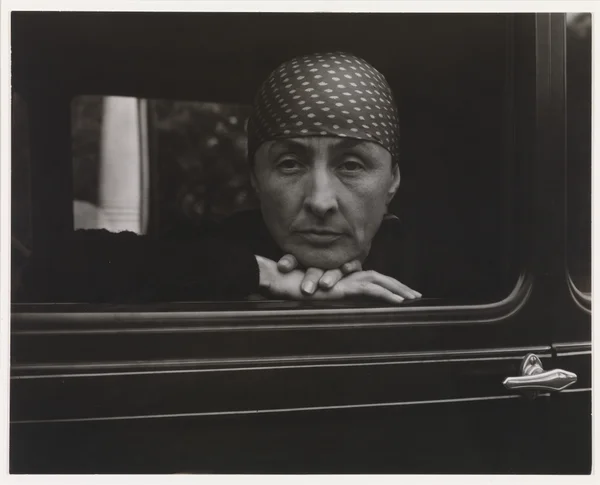 georgia-o-keeffe front-face-portrait-with-head-cover-in-a-car-window female