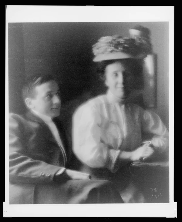 young-man-suit-woman-white-blouse-hat-seated-portrait male-female